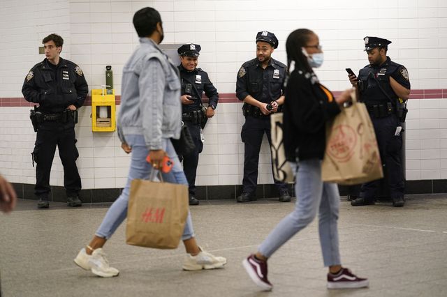 Officers have their backs on a wall patrolling a subway station.